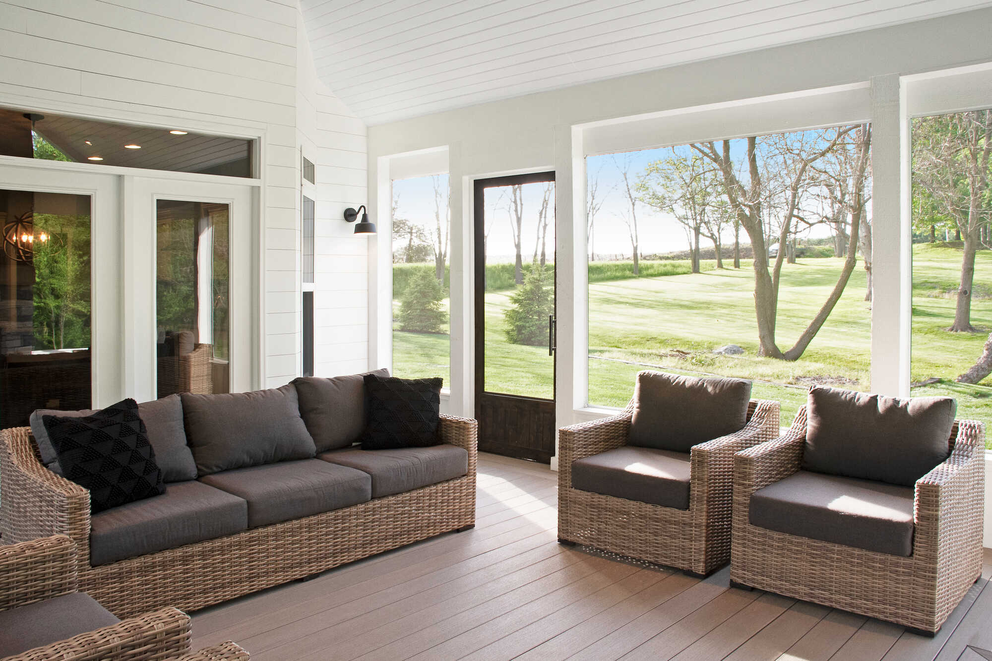 Neutral-toned screened porch with shiplap walls and views of a landscaped backyard, created by S. Brown Construction Co., Indiana.