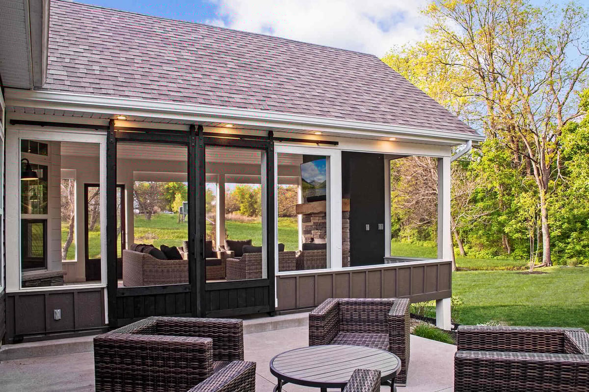 Custom outdoor living room with screened walls and a stone fireplace, built by S. Brown Construction Co. in Wildcat Creek, IN.
