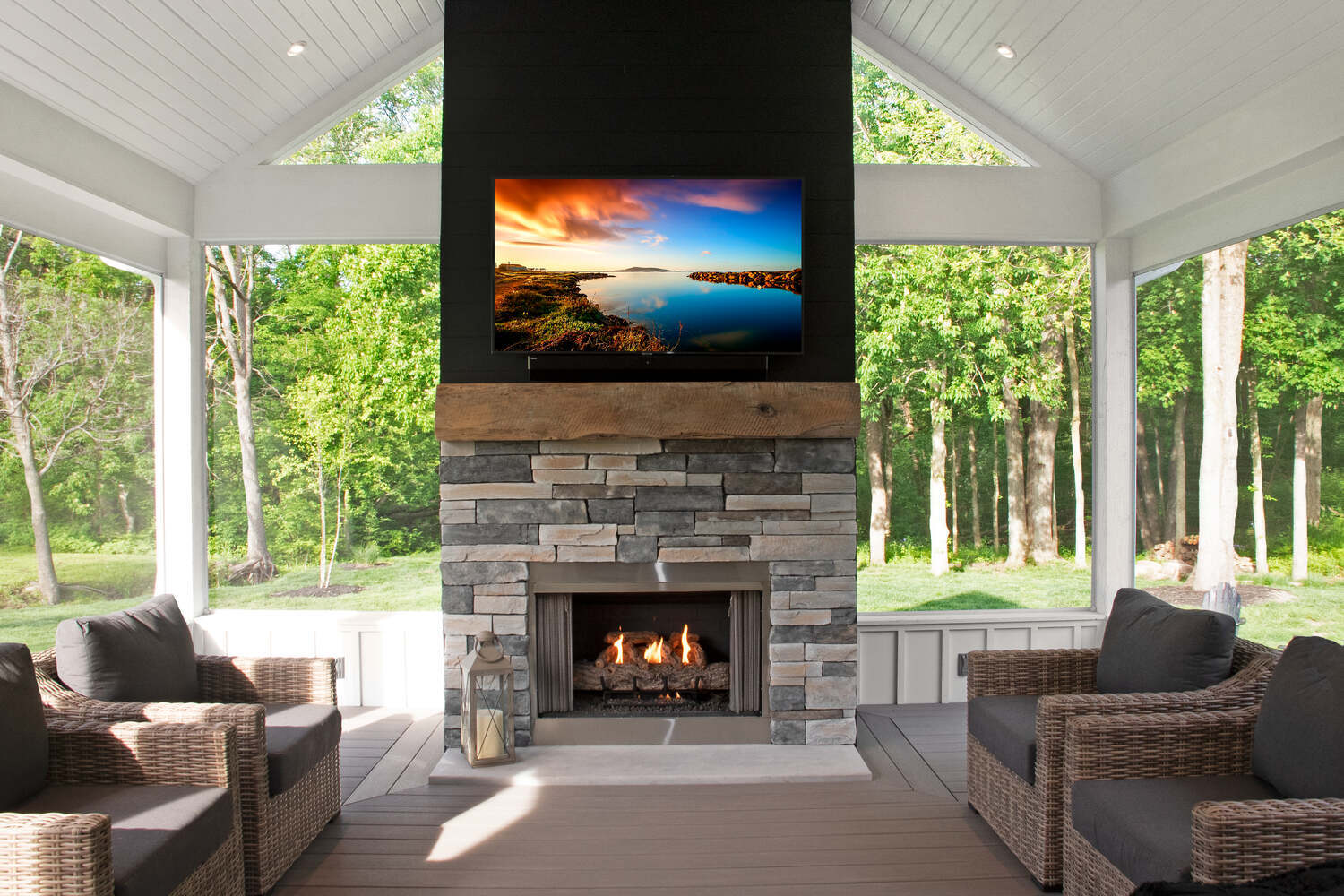 Interior of a bright and airy screened porch with wicker furniture and wide windows, by S. Brown Construction Co., Indiana.