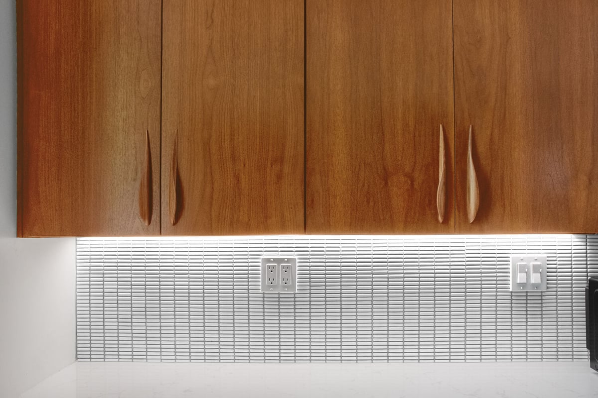 Close-up of custom wood cabinetry and backsplash lighting in Arbor Chase, IN kitchen by S. Brown Construction Co.