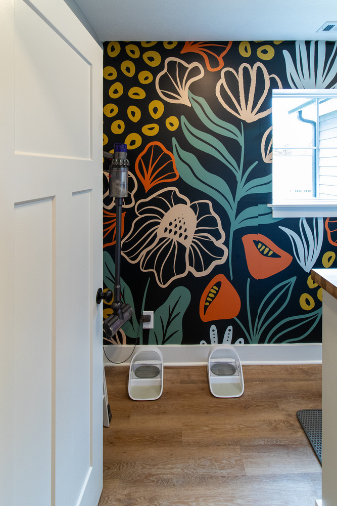 Vibrant mudroom design featuring bold wall art and pet feeding area in Arbor Chase, IN by S. Brown Construction Co.