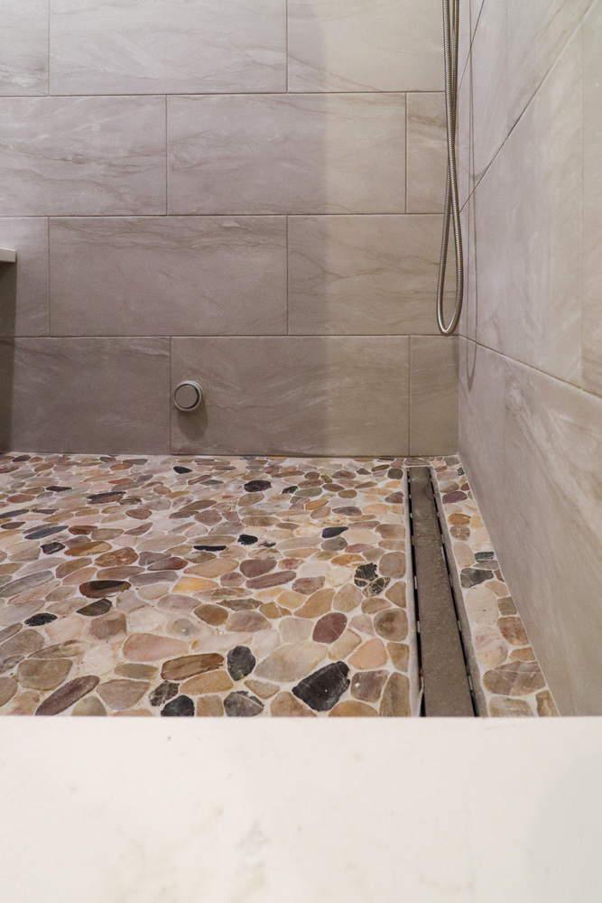 Close-up of natural pebble shower floor in custom bathroom by S. Brown Construction Co. in Buck Creek, IN.