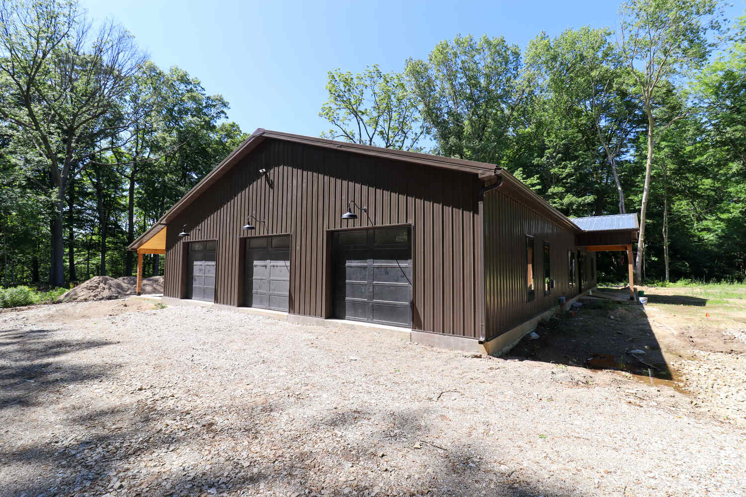 Rear view of brown metal barndominium with three garage bays by S. Brown Construction Co. in West Lafayette, IN.