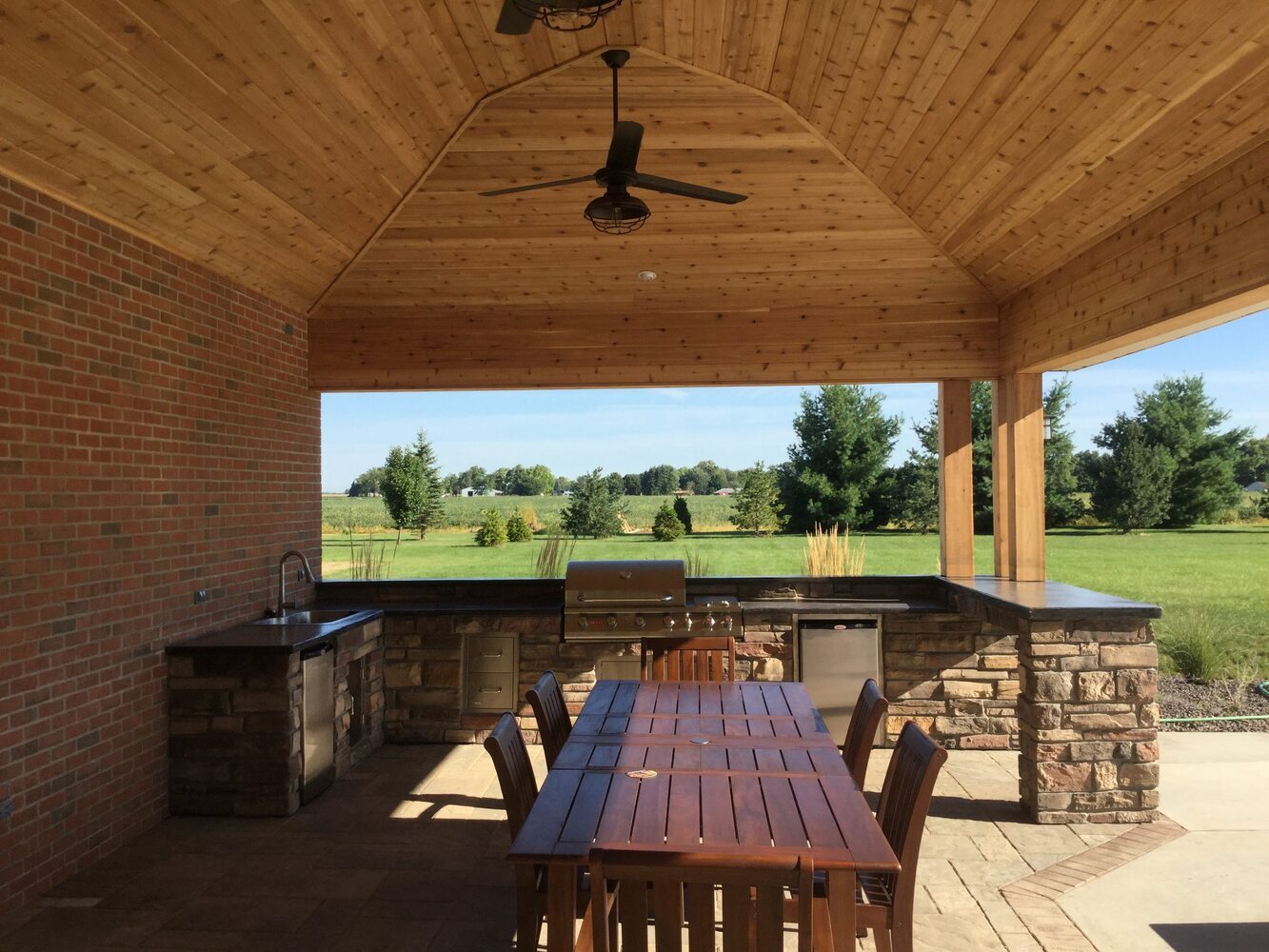 Covered outdoor kitchen and seating area with brick and stone finishes by S. Brown Construction Co. in West Lafayette, Indiana.