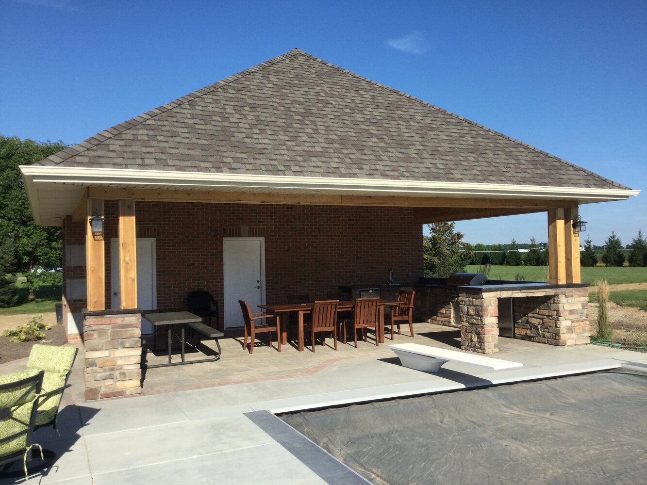Custom poolside pavilion with outdoor dining area and built-in grilling station by S. Brown Construction Co., located in Lafayette, Indiana.
