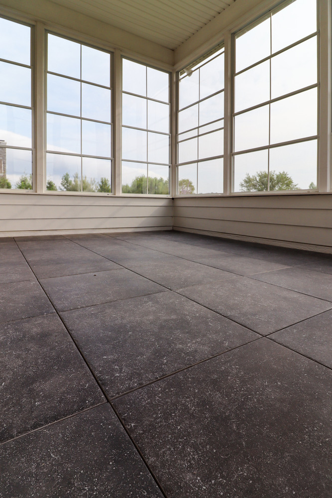 Interior view of a screened-in sunroom with large gray tile flooring, built by S. Brown Construction Co. in Arbor Chase, Indiana.