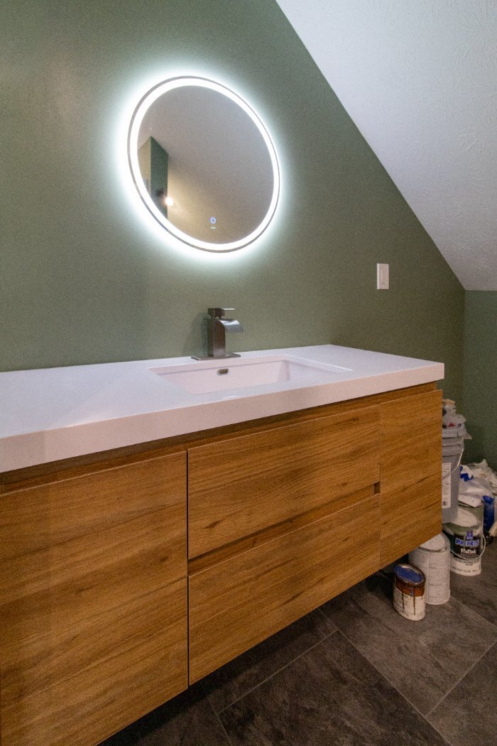 S. Brown Construction Co. Schoon Garage Addition lighted round mirror above a modern vanity in the finished bathroom in Lafayett-optimized